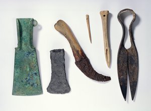 Selección de herramientas: de izquierda a derecha: hacha de bronce de la Edad del Hierro temprana con alas dobladas; hacha de hierro posterior; cuchillo con mango de hueso; aguja de hueso; punzón de hueso; tijeras de hierro